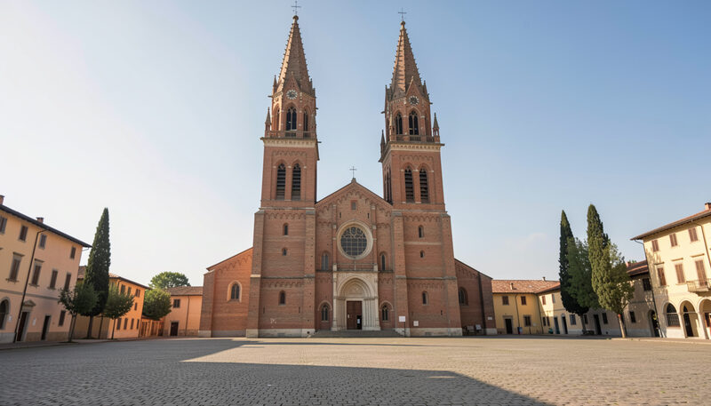 Medeltida tegelkyrka med två höga torn mot klar himmel och tomt kullerstenstorg framför.